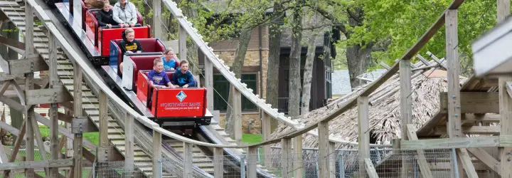 Children riding a roller coaster as it reaches the bottom of a drop.