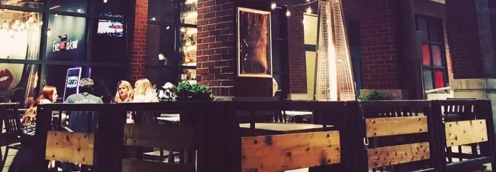 A group of friends enjoy drinks on a bar's patio at night.