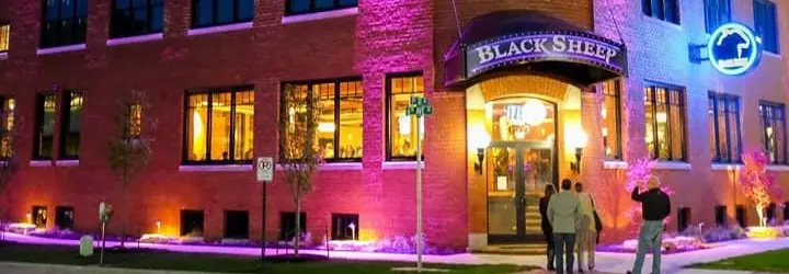 A group walking into a tan brick building illuminated by purple lights.