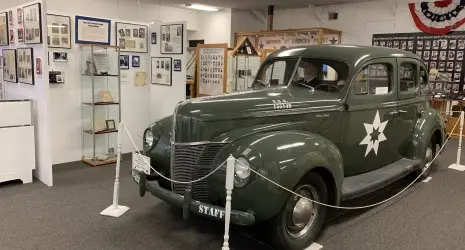 An old WWII beatle car sits in front of a variety of photos and informational displays.