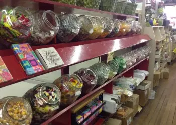 Red shelves filled with jars of colorful candy on display inside a candy store. 