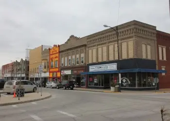 A historic main street featuring a collection of brick-walled businesses and parked cars.