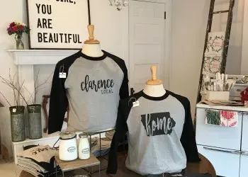 Mannequins wearing baseball-style shirts with "Clarence, Iowa" and "Home" on display inside a store.