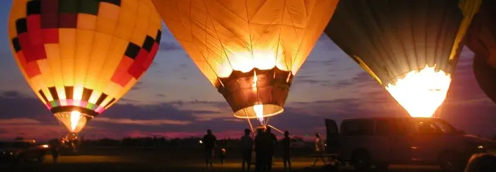 Three grounded hot air balloons light up in the night. 
