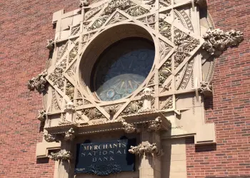 The iconic Merhants National Bank's upper circular window surrounded by intricate stone carvings.
