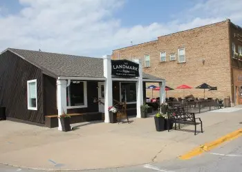 A quaint brown-sided restaurant with white beams and outdoor seating.