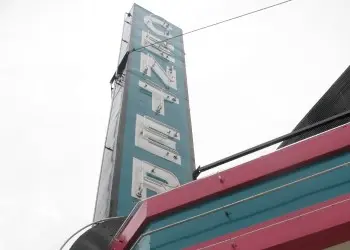 Looking up at a historic metal green marquee for the Center Theatre.