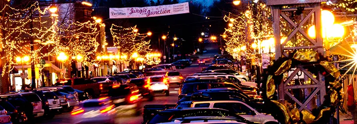 A street in lined by cars and bright Christmas lights.