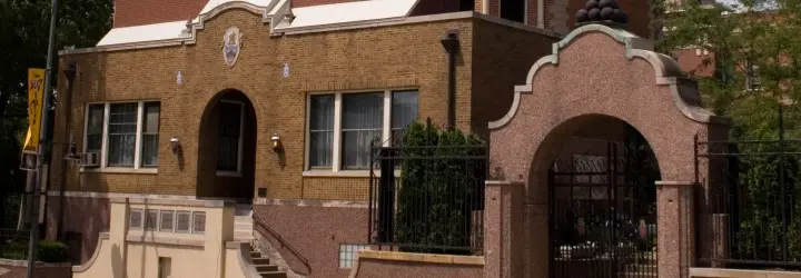 A brick home featuring arched front entrances and a black iron fence.