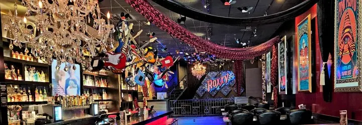 The interior of a bar featuring decorative chandeliers and red tapestries.