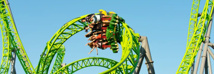 IA rollercoaster completes a flip as riders hands float above their heads.