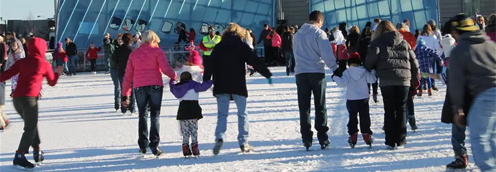 A crowd of ice skaters skates around a rink. 