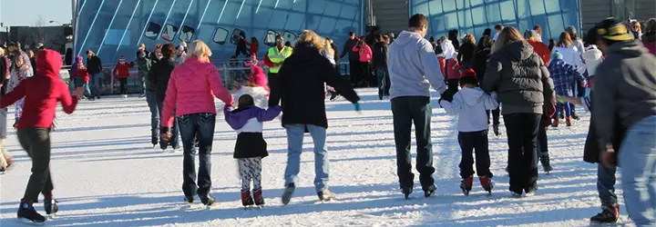A crowd of ice skaters skates around a rink.