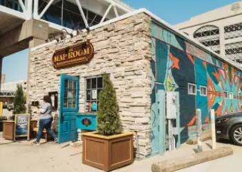 The stone exterior of the Map Room restaurant with a colorful mural around the corner.