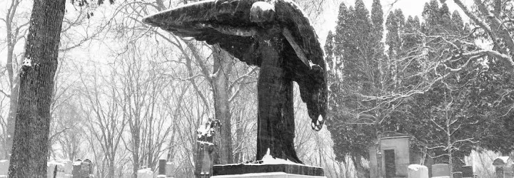 An eery statue of a blackened angel looms above gravestones. 