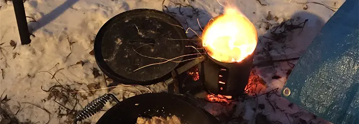 A small winter campfire sits on a snow-covered ground.