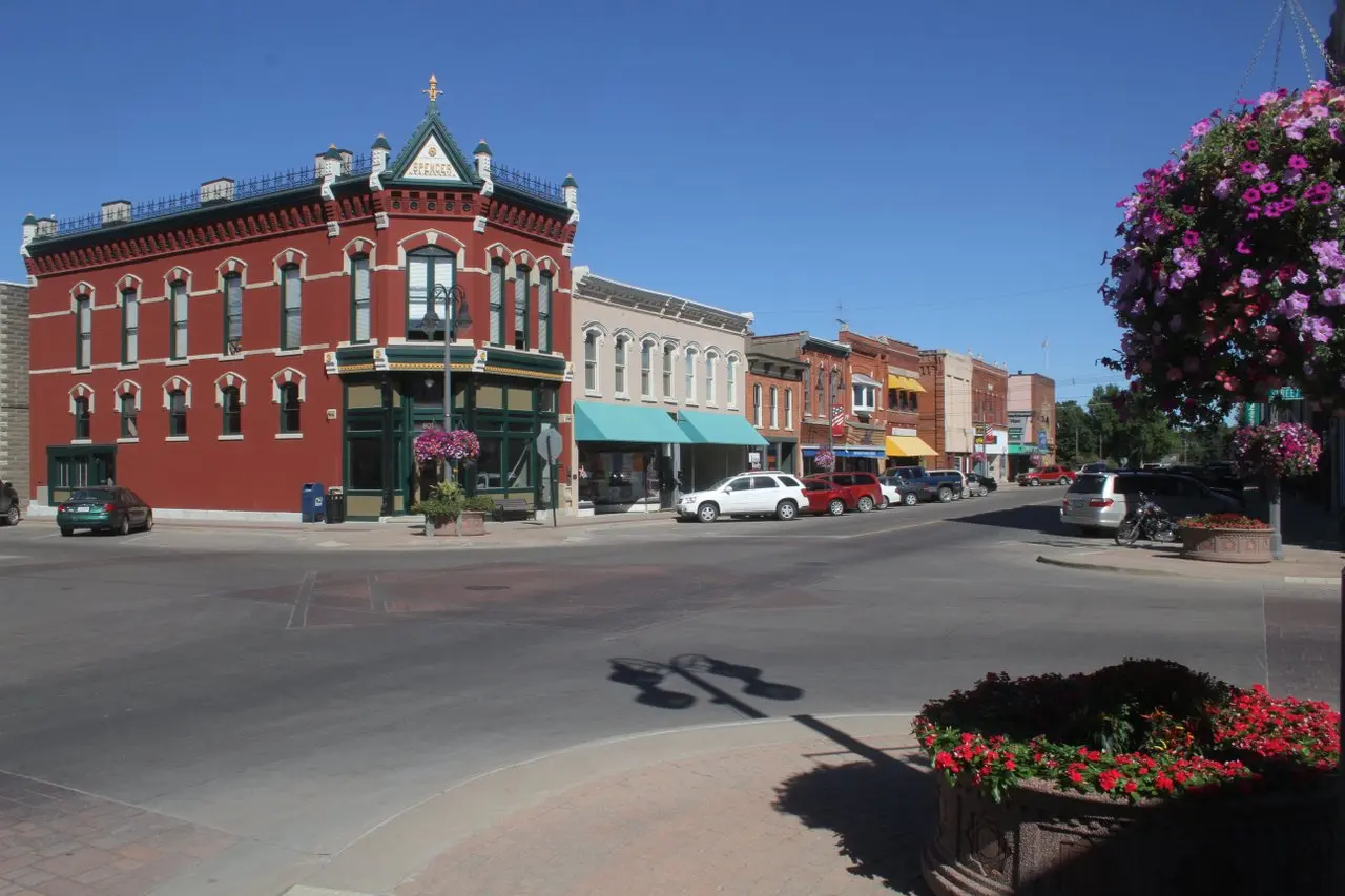 A historic main street lined by pink flowers in baskets. 