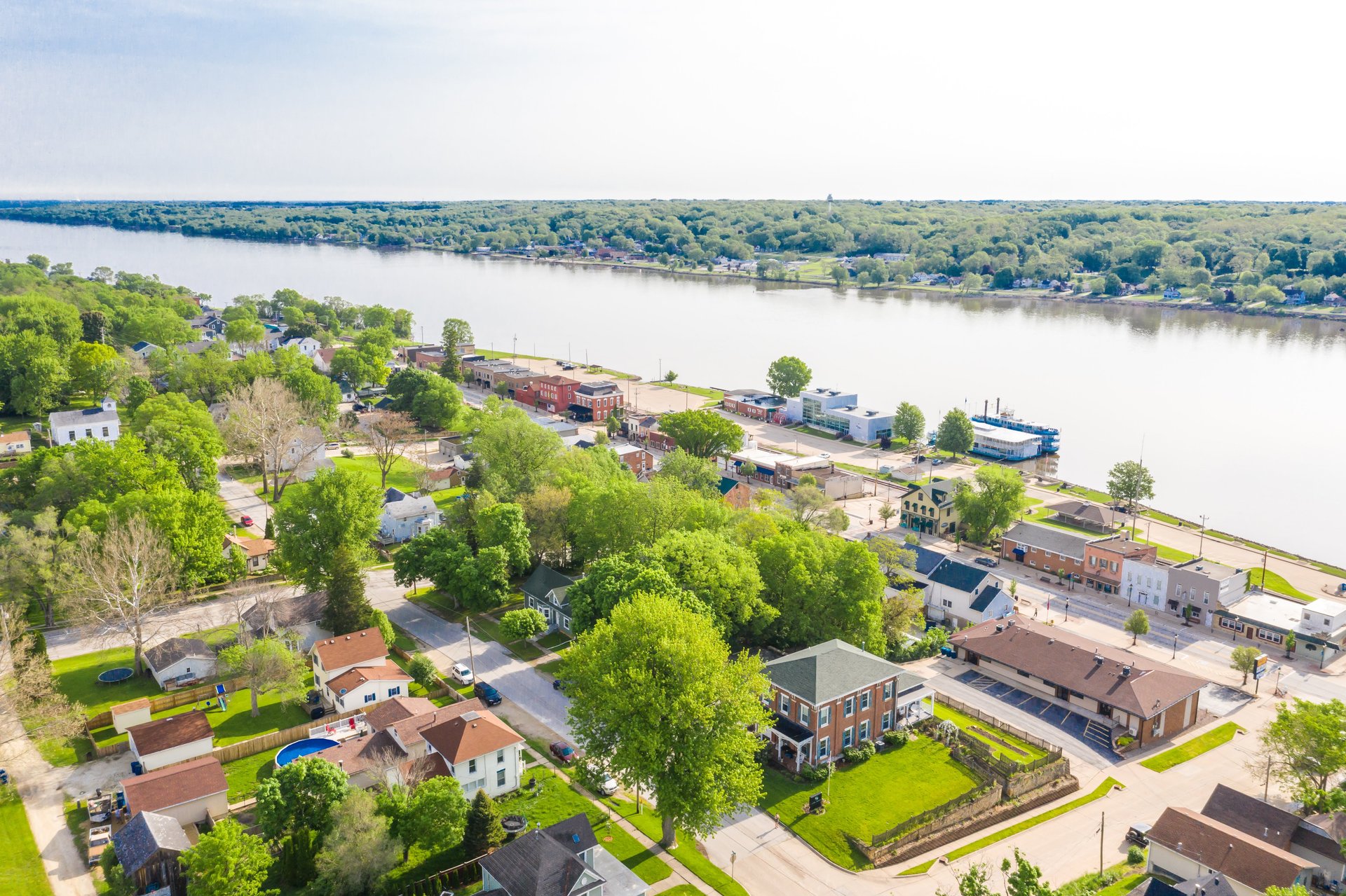 An aerial view of a charming community on the shores of a wide river.