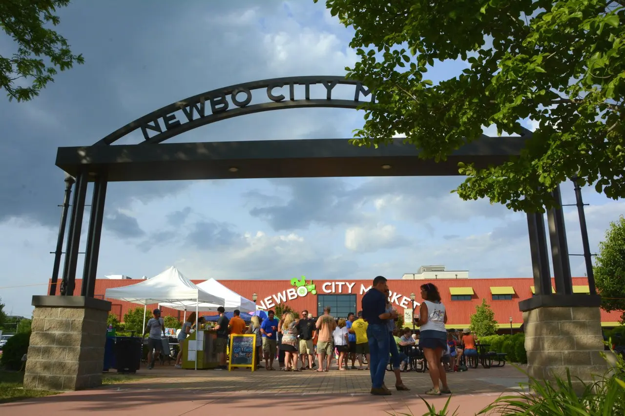 A couple walks beneath an arch to the Newbo City Market brick building.