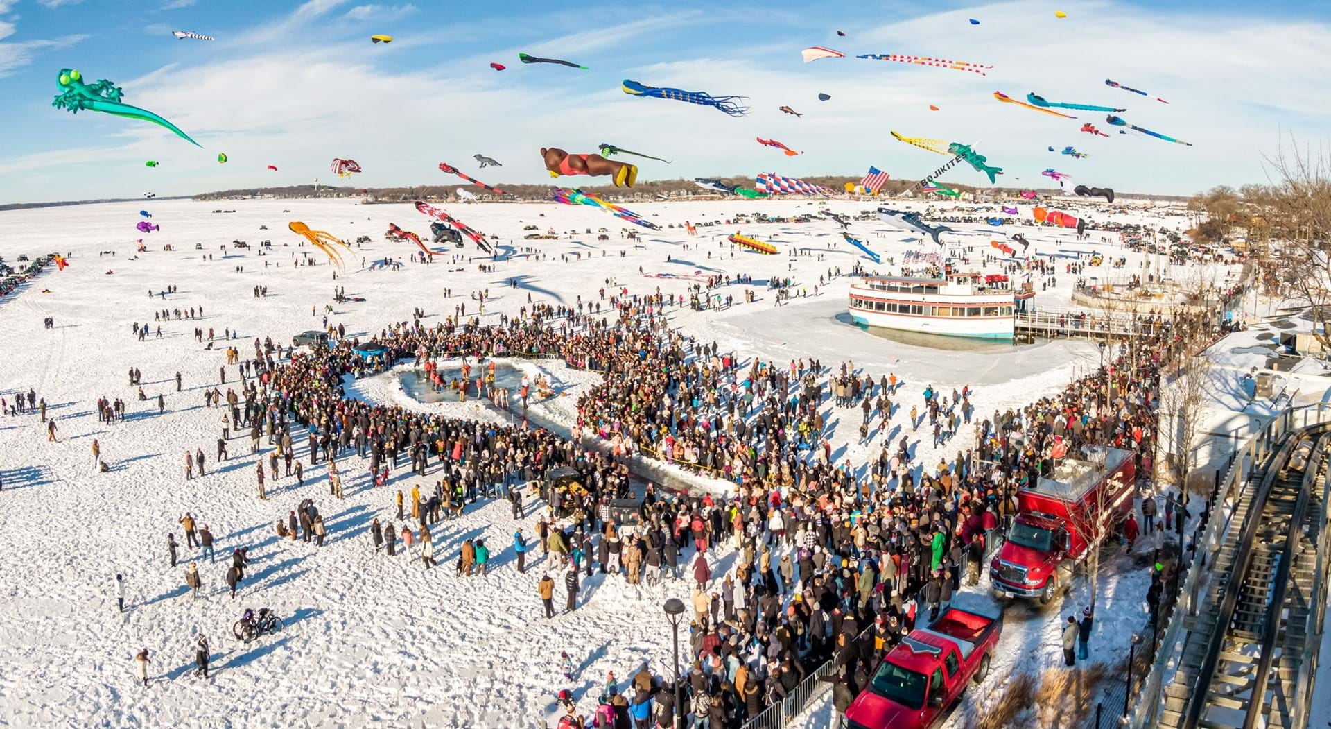 Kites fly over the lake during the University of Okoboji Winter Games Polar Plunge.