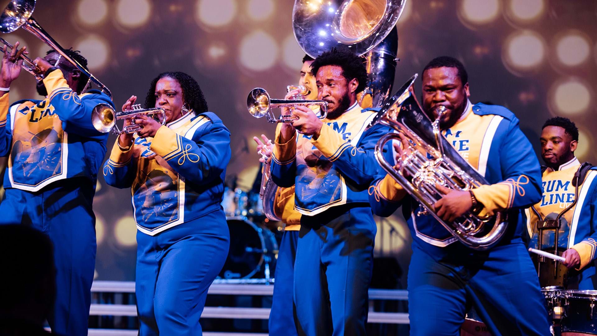 A group of performers in blue band costumes holding instruments performing 