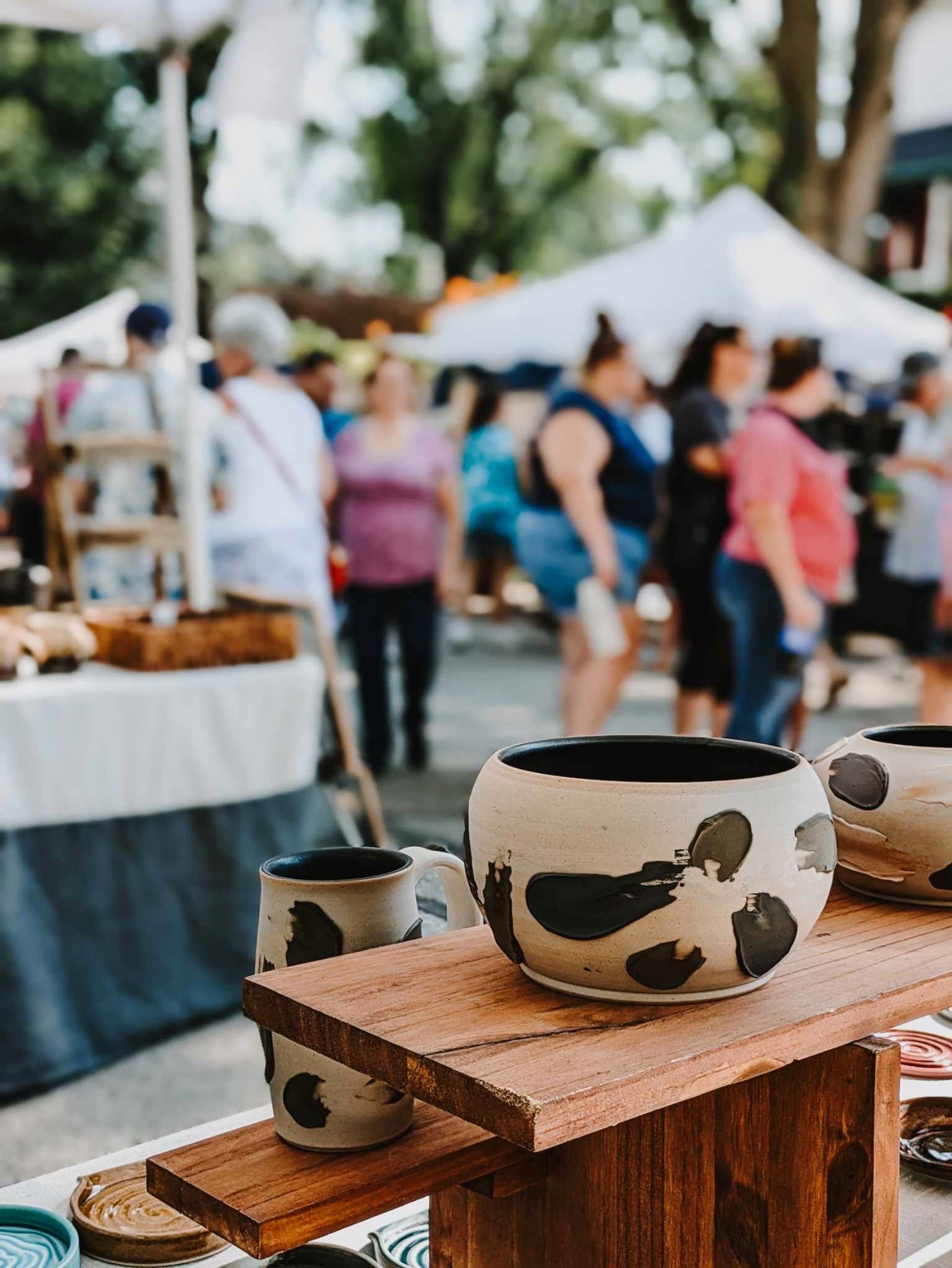 Piece of pottery on display with fair goers in the background at the Snake Alley Art Fair 2024.