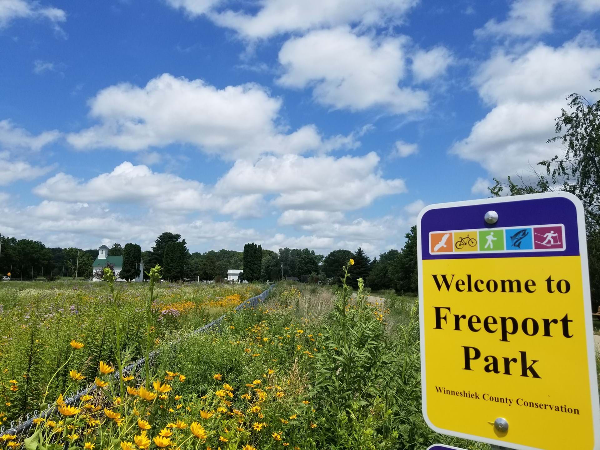 The sign welcoming you to Freeport Park, overlook a fieel of wildflowers and grasses