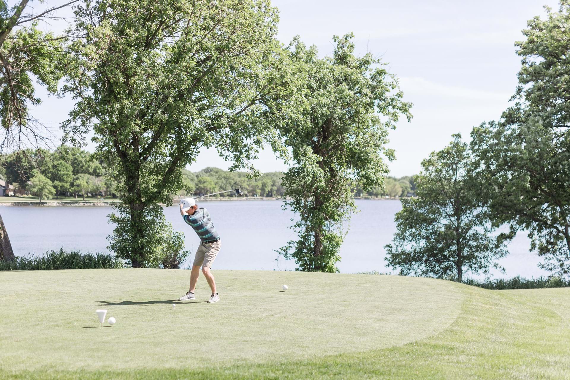 Golfer teeing off on lakeside hole